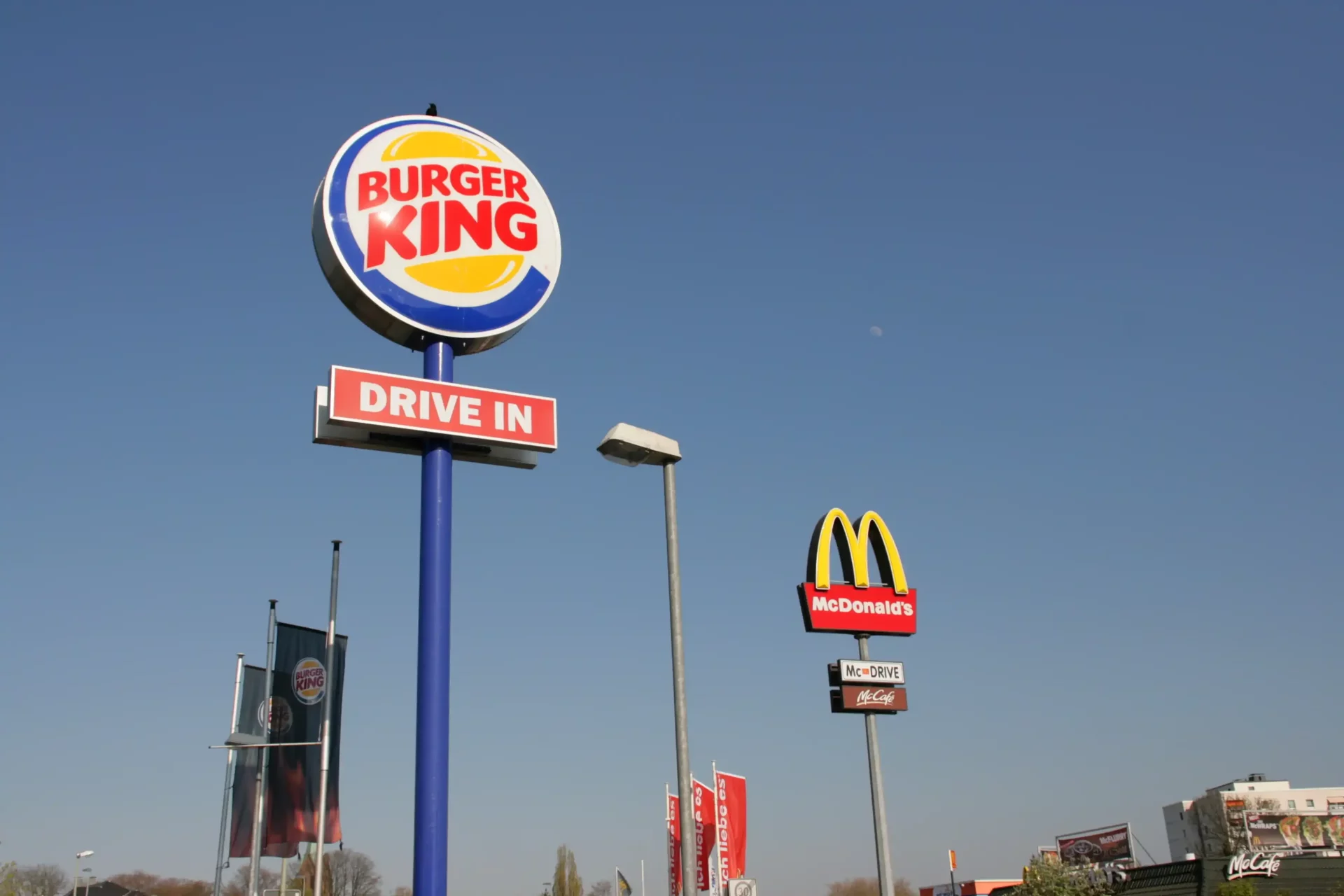 Carteles de Burger King y McDonald's en una carretera, representando la competencia estratégica entre cadenas de comida rápida.